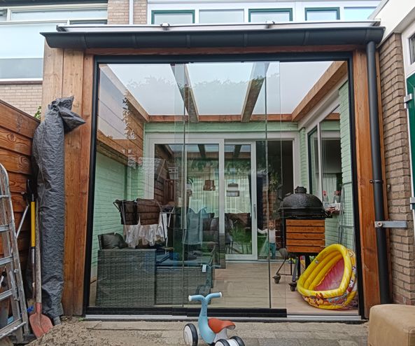 Douglas overkapping met polycarbonaat dak en glazen schuifwand.